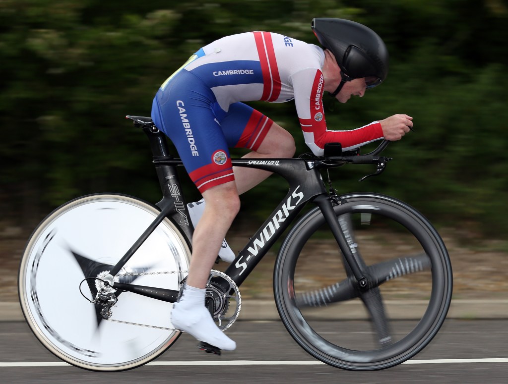 Cyclist pushing hard on the pedals, riding with intensity and focus, framed by springtime countryside — the energy of breaking through and moving forward.