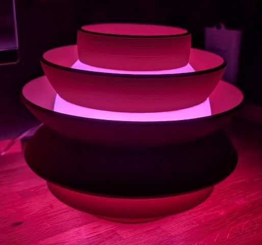 Spin Light illuminated with red and pink tones, showing nested circular shapes and soft light diffusion
