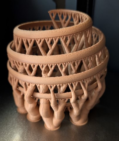 3D-printed spiral sphere with complex support structures clinging to the model like stagehands holding up scenery.