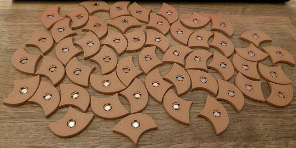 Back of Penrose tiles with shiny silver magnets locked in place, ready to stick to anything metal that wanders too close.